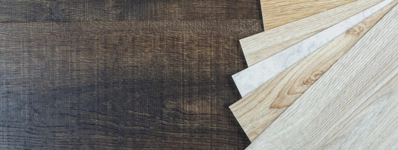 Fünf helle Laminatbodenmuster werden auf einer dunklen Tischplatte ausgestellt.