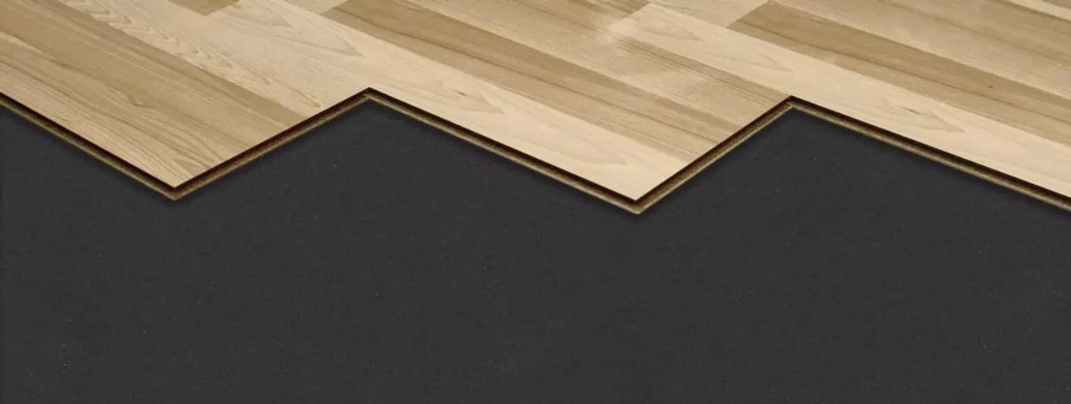 Holzbodenfliesen mit ineinandergreifenden Zickzackkanten, die auf einer akustischen Unterlage verlegt werden.